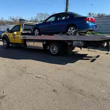 A.C.A. flatbed with a blue sedan loaded and strapped down